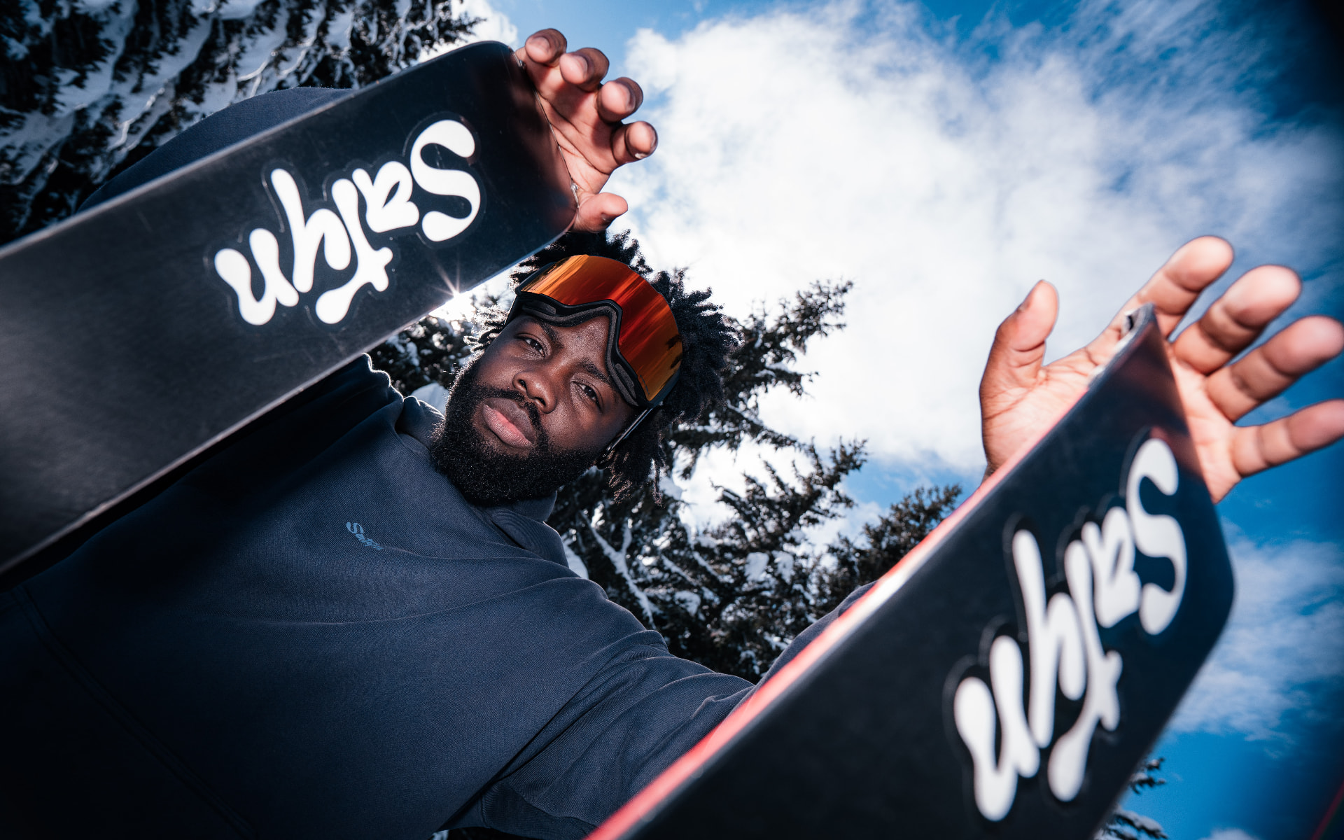 Skieur tenant des skis Satin sous un ciel bleu